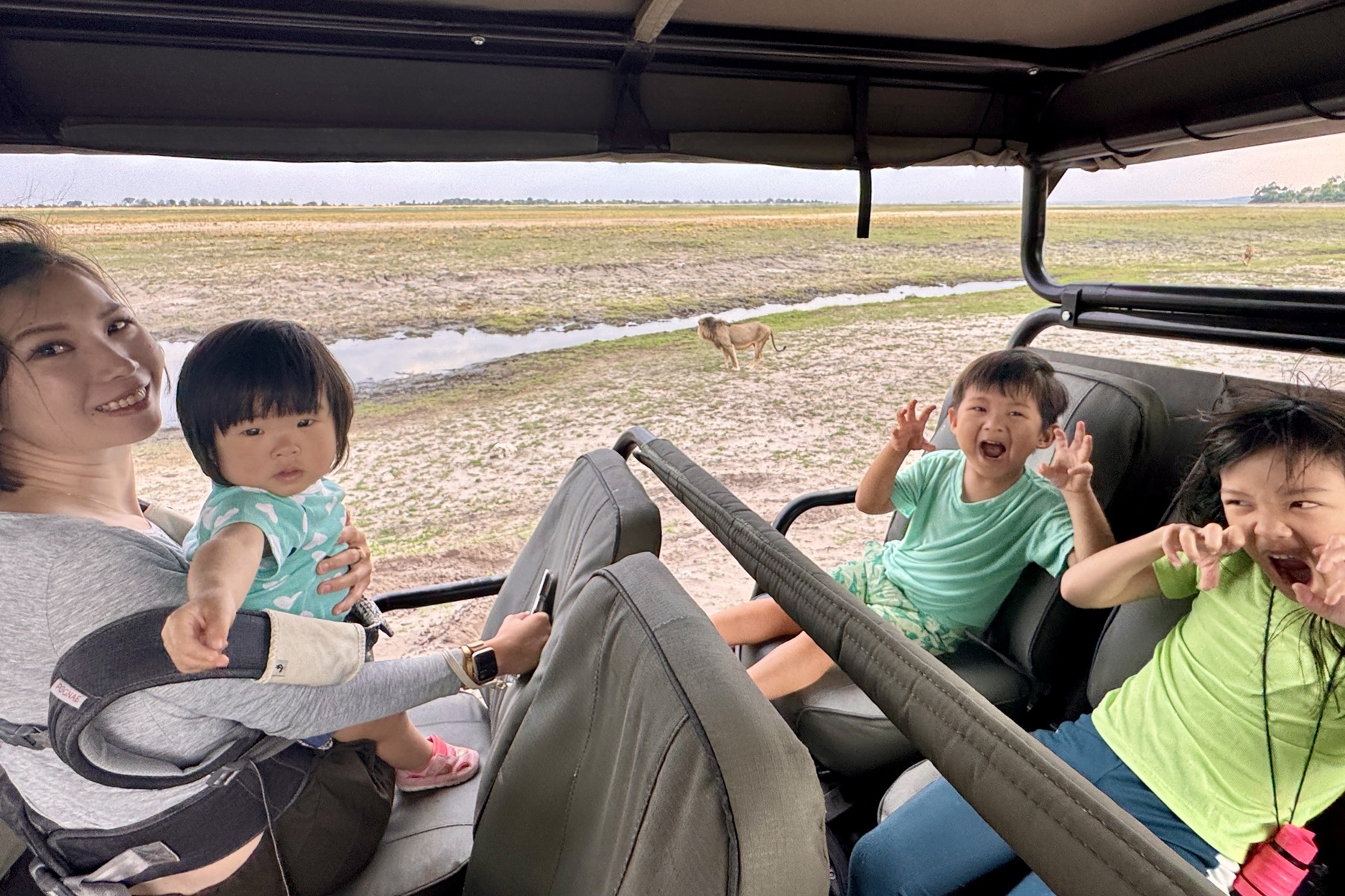 The children with a lion behind them on safari