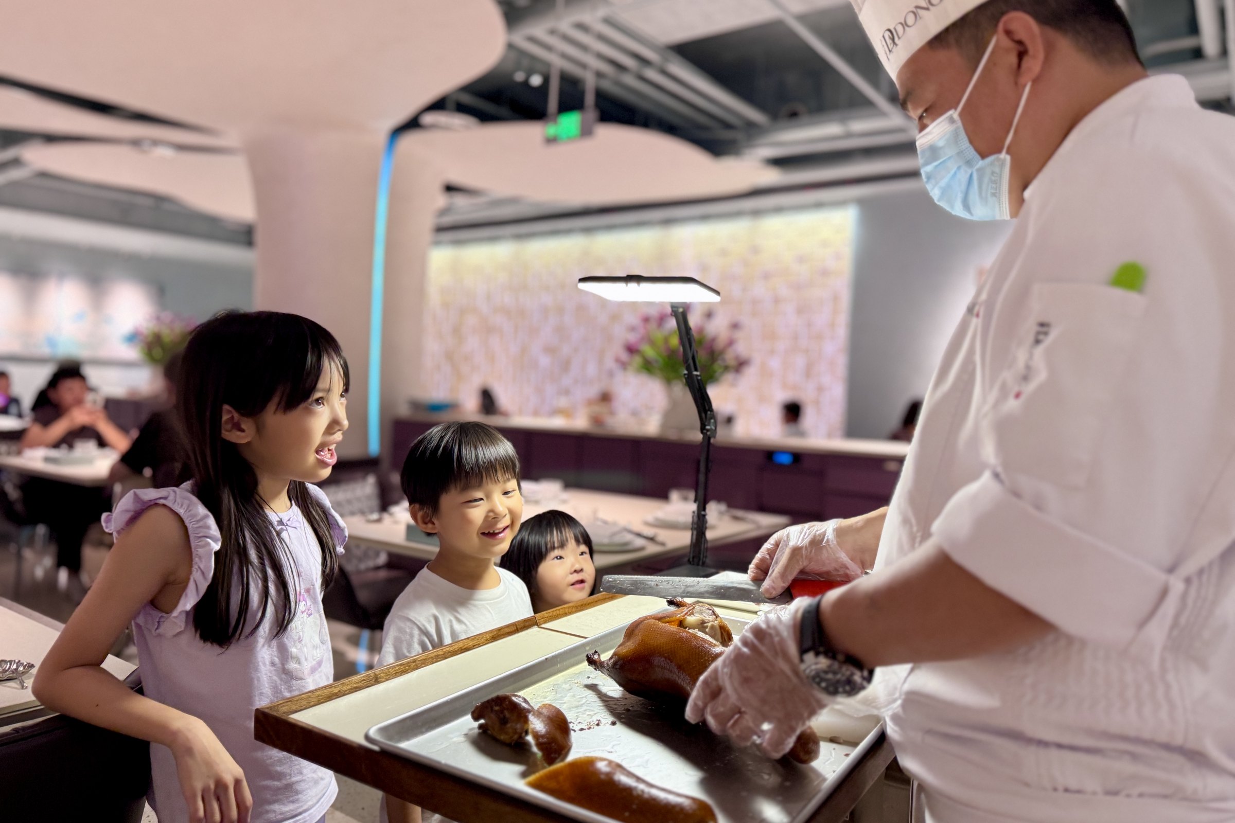 The children watching roast duck being carved at Da Dong