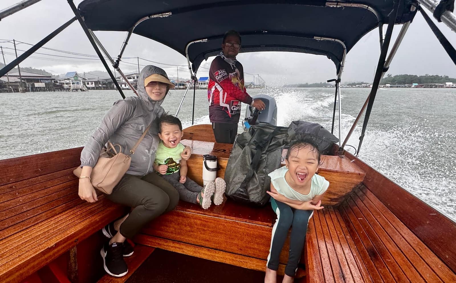 Vanessa, Sophie and George riding through Kampong Ayer by longboat in the rain