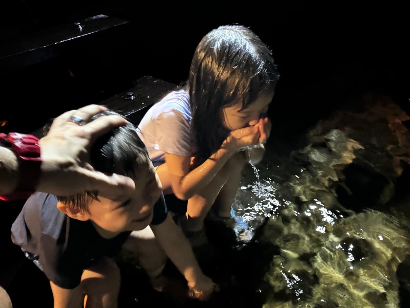 Sophie and George drinking the clear water inside the cave