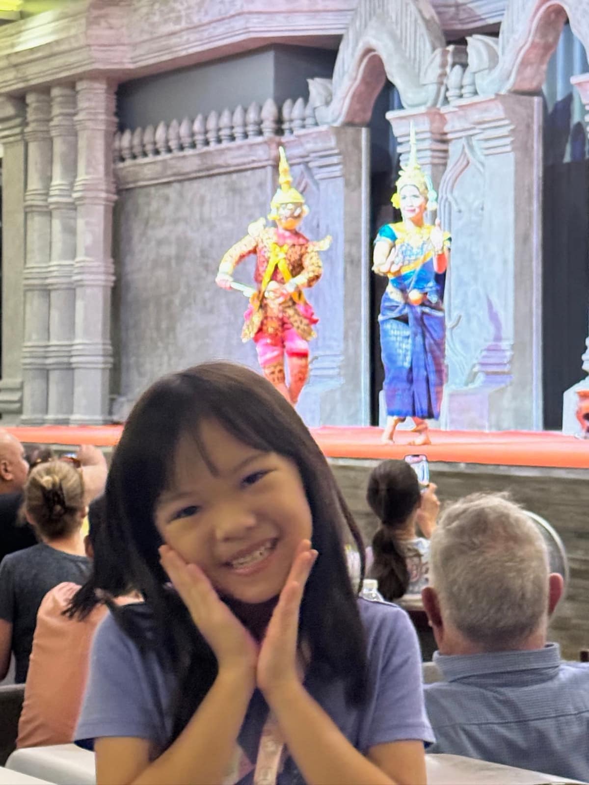 Sophie smiling in front of the Apsara dancers during dinner in Siem Reap