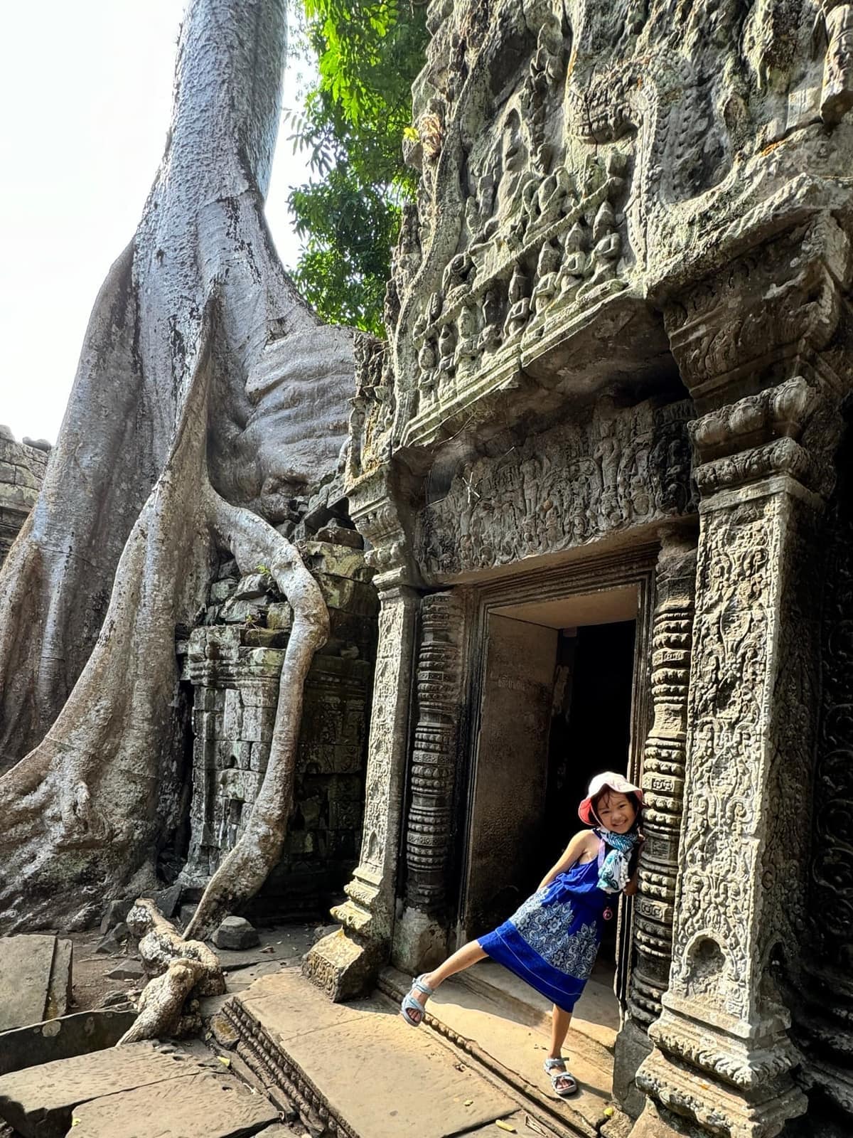 Sophie standing in a temple doorway framed by large tree roots at Angkor