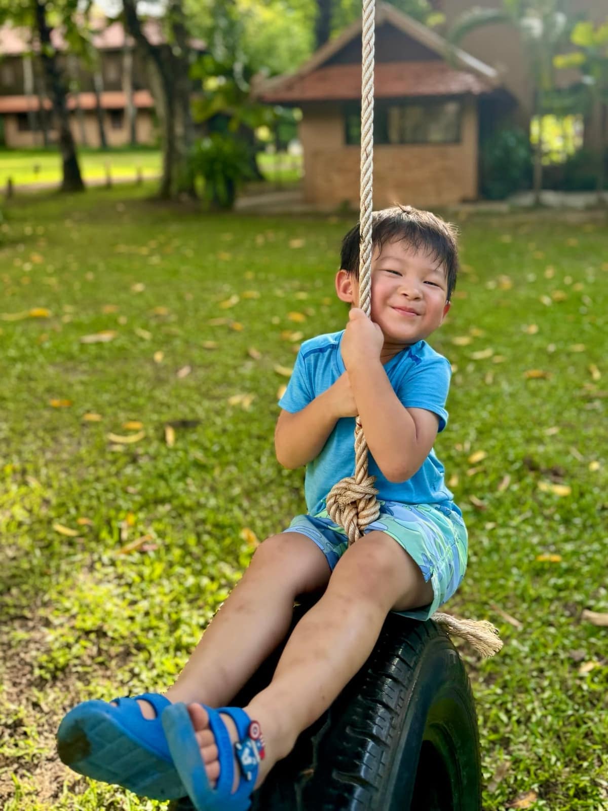 George sitting on a rope swing in the hotel garden