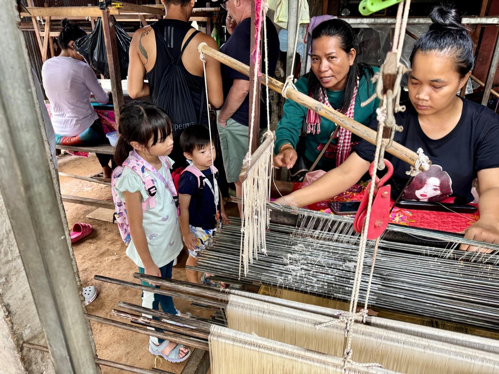 The children watching a weaver working at a loom on Koh Dach