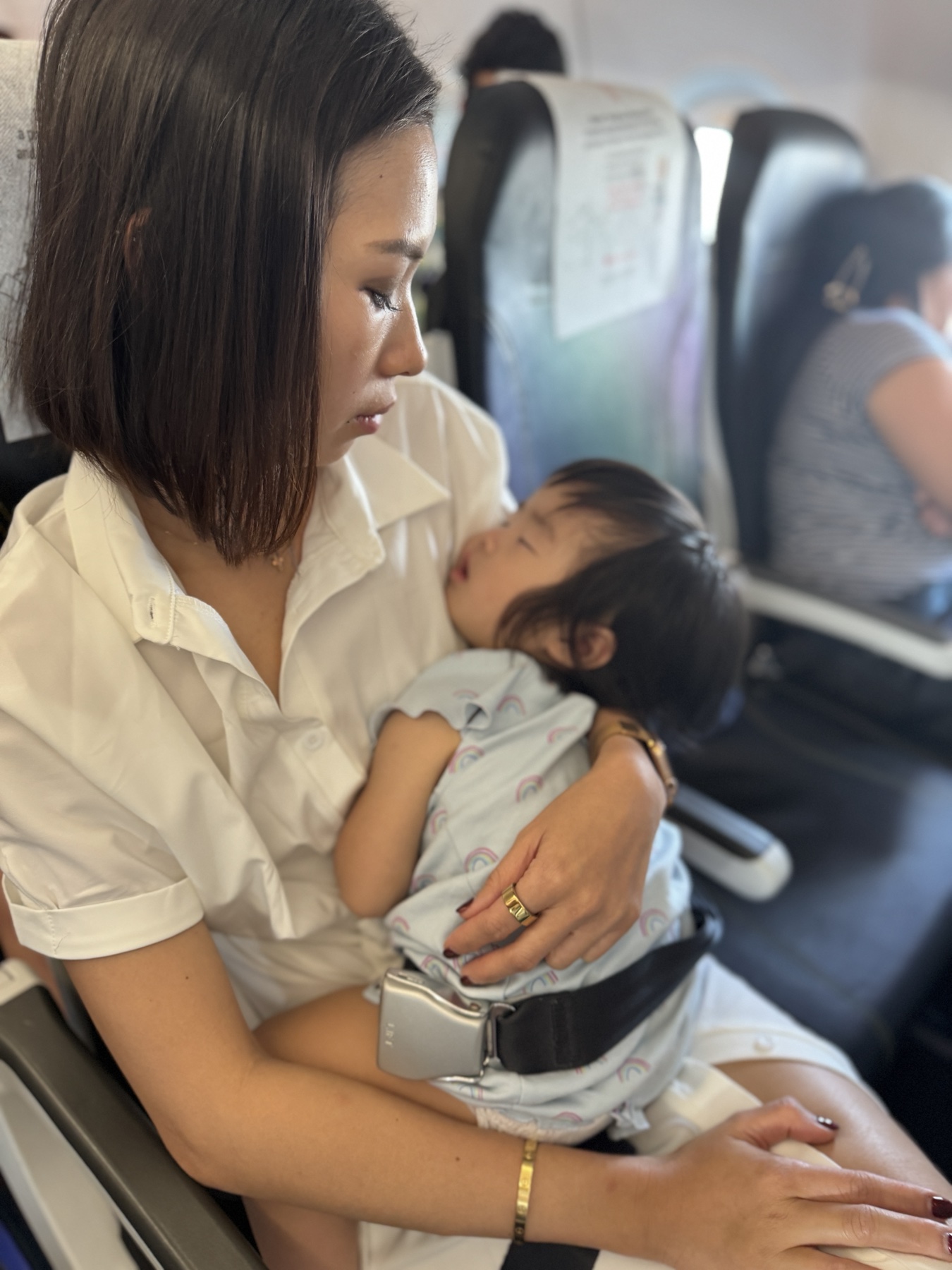 Claire asleep in Vanessa's arms on the flight home