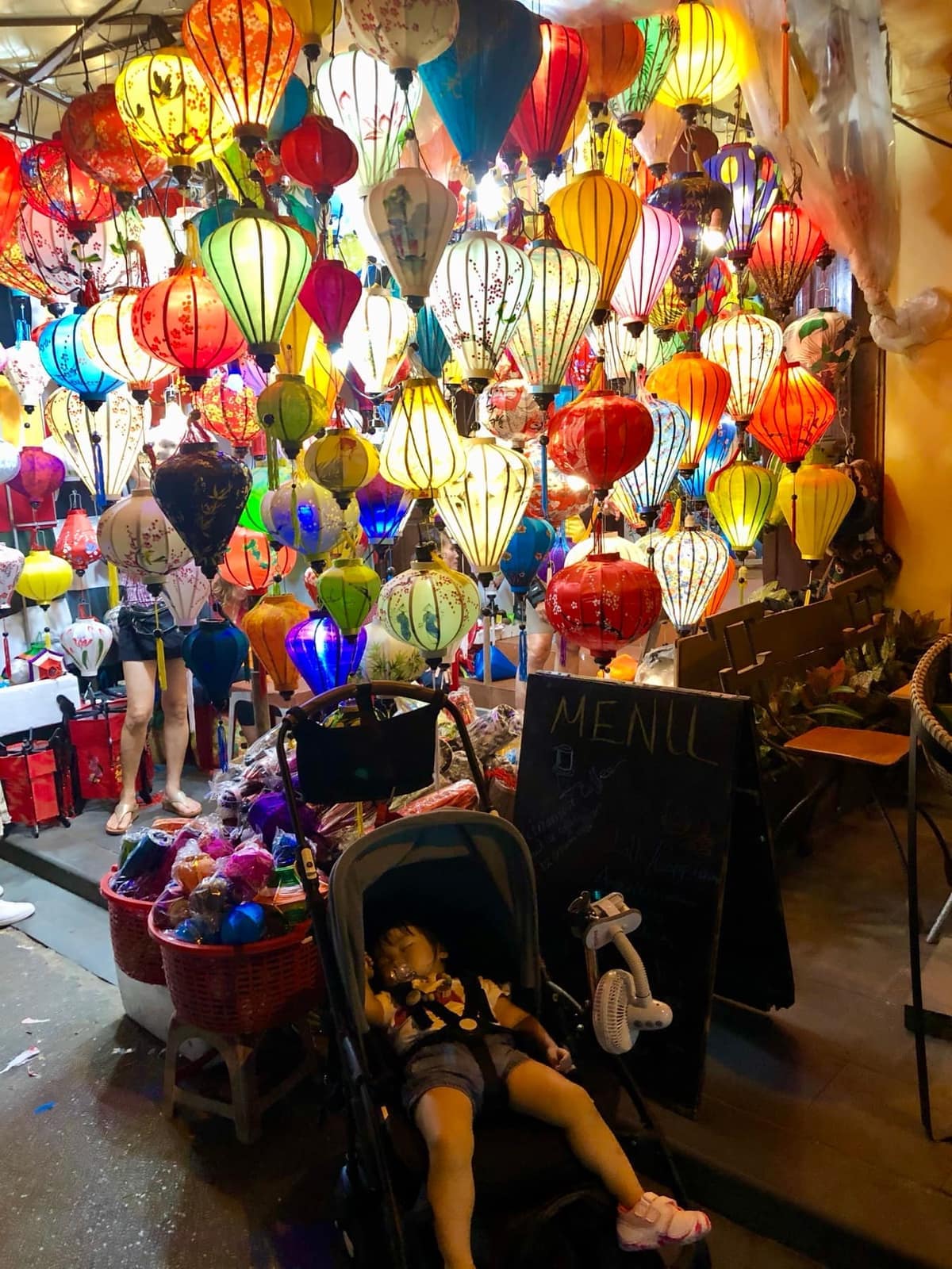 Sophie asleep in her stroller beneath a dense display of colourful Hoi An lanterns