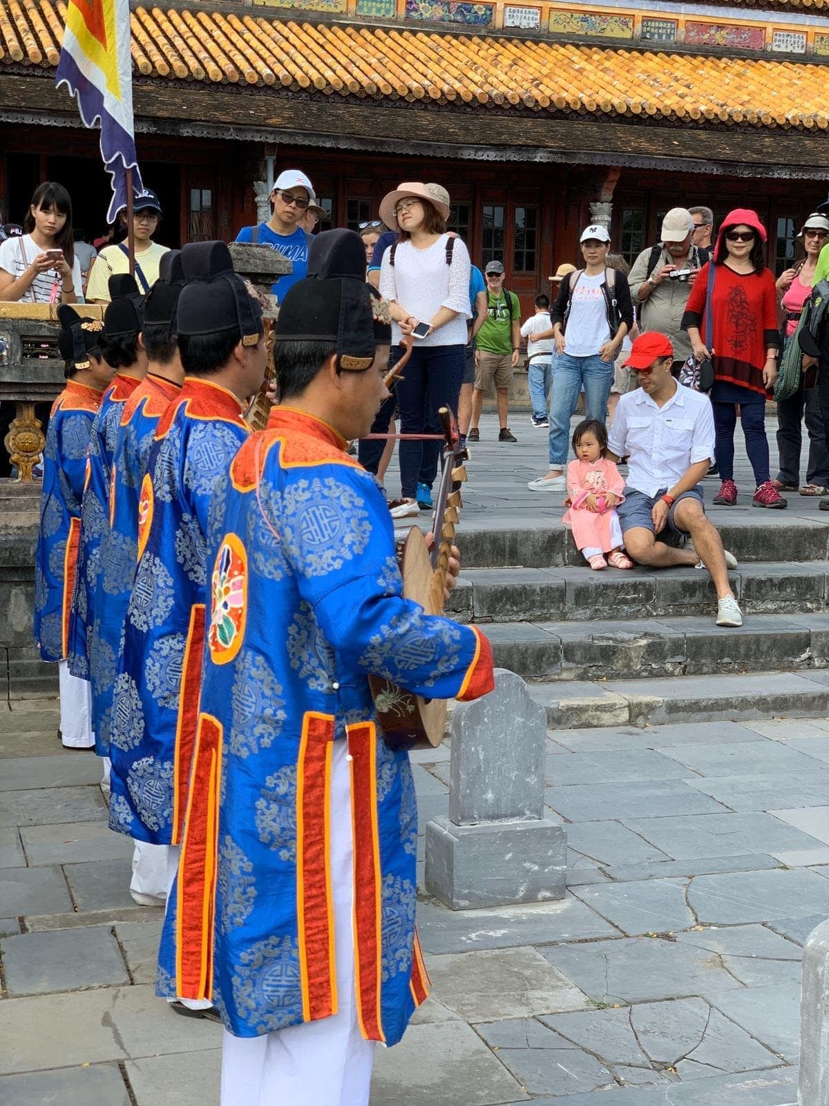 Traditional musicians performing while Philip and Sophie watch from the courtyard steps