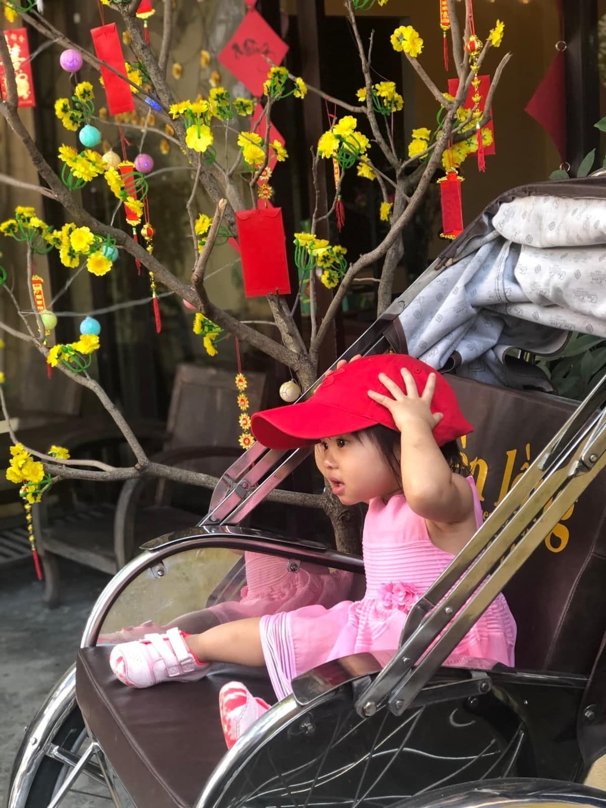 Sophie sitting in a cyclo beside decorations for Tết
