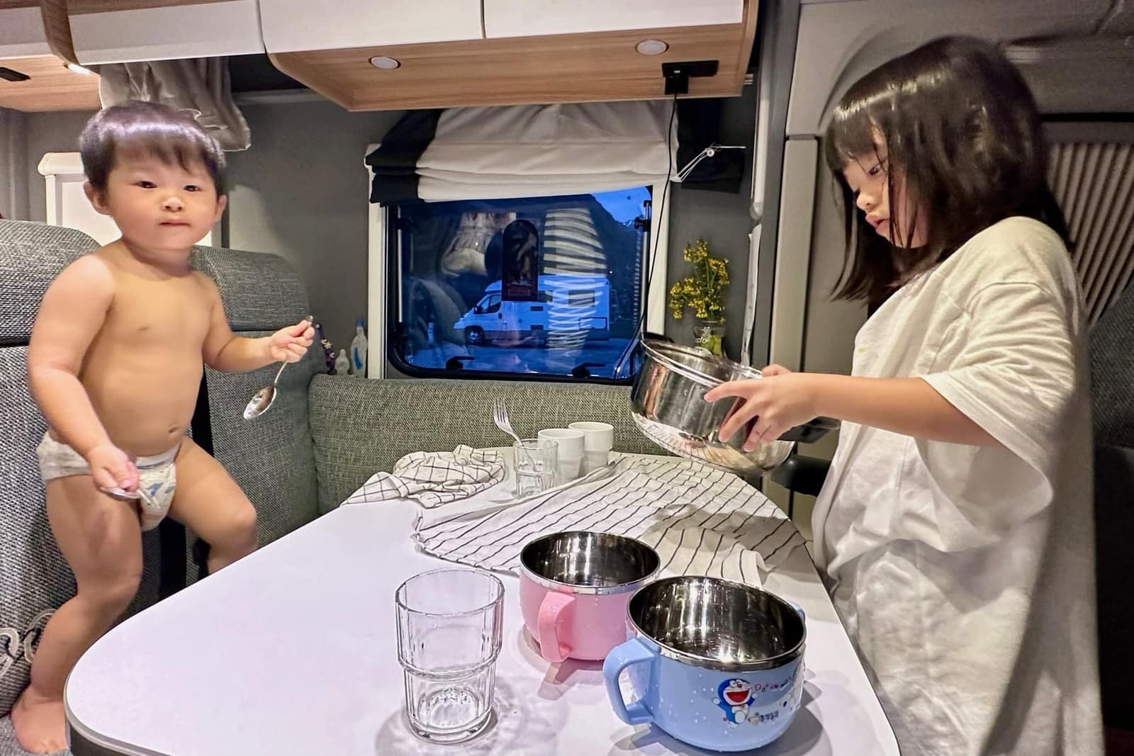 The children drying dishes inside the motorhome