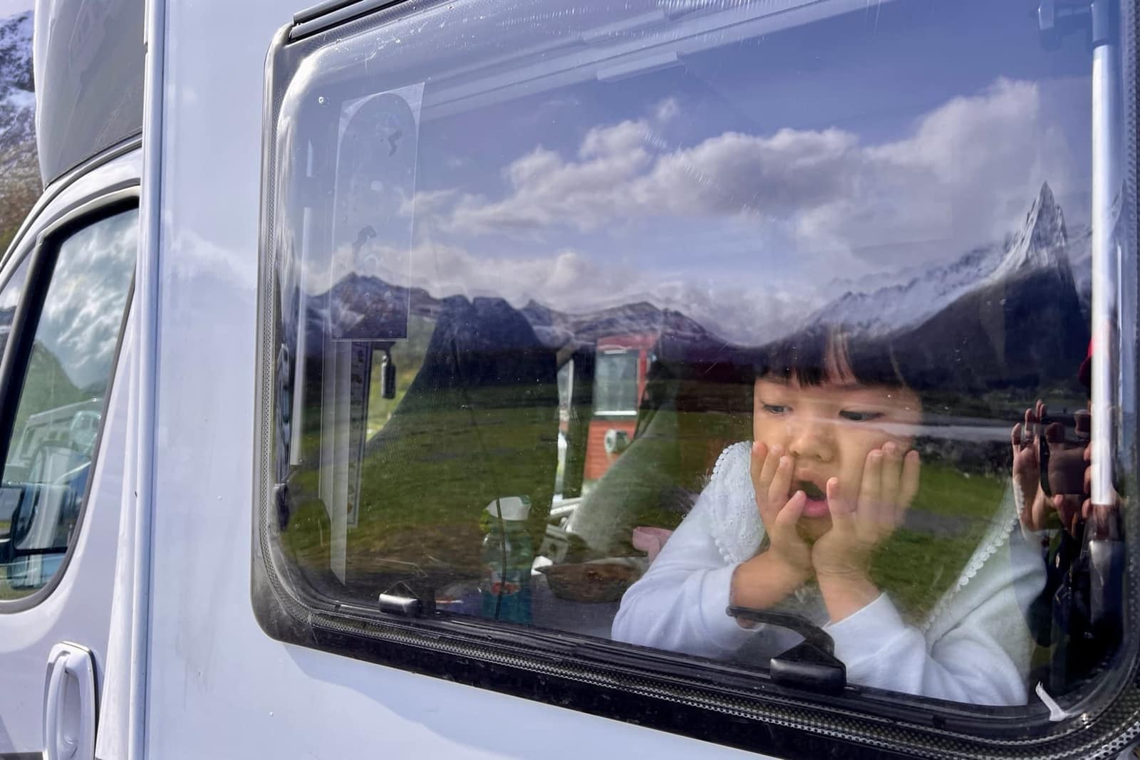 A child looking through the motorhome window in Lofoten