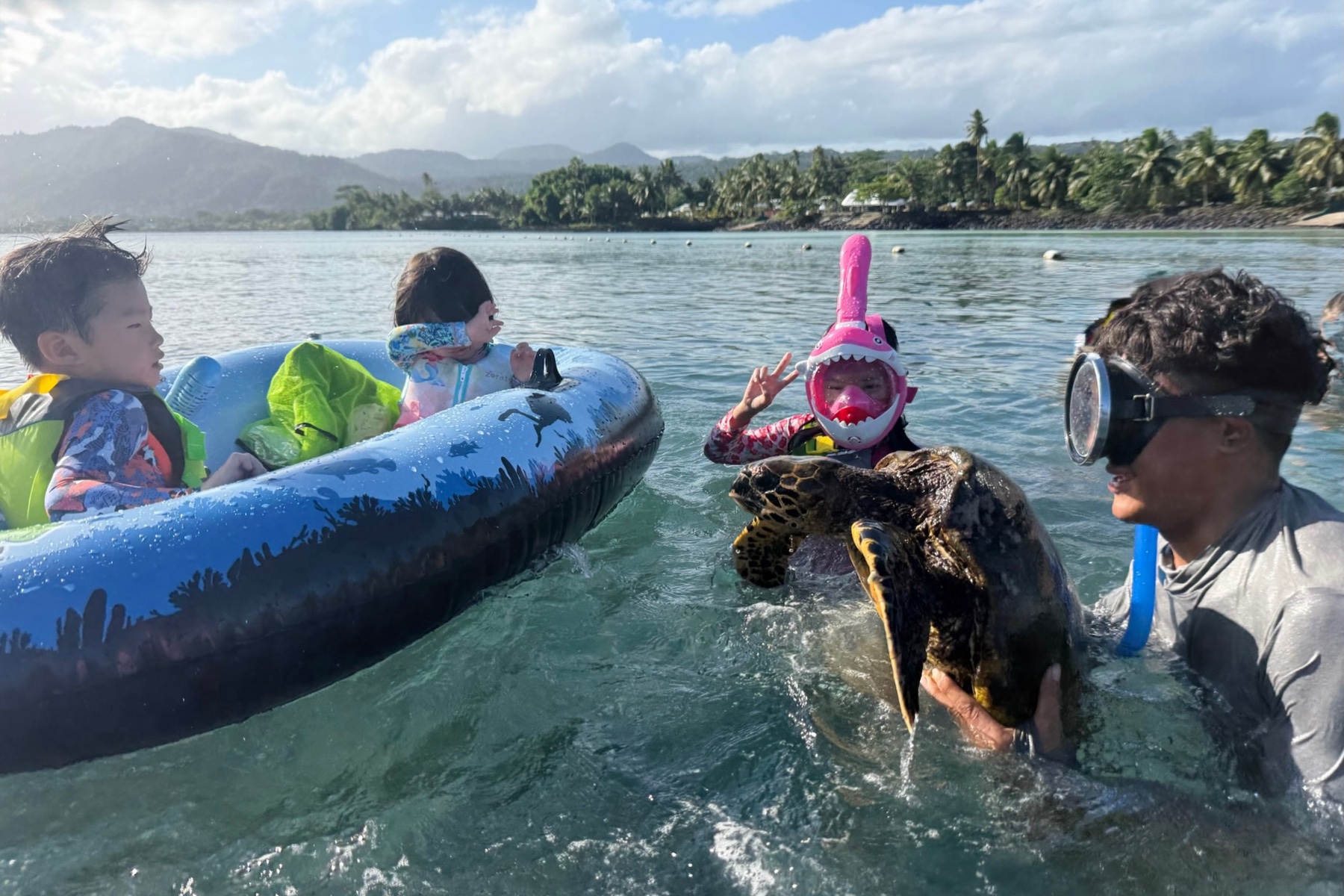 The local chief’s son showing the children a turtle at the Giant Clam Sanctuary