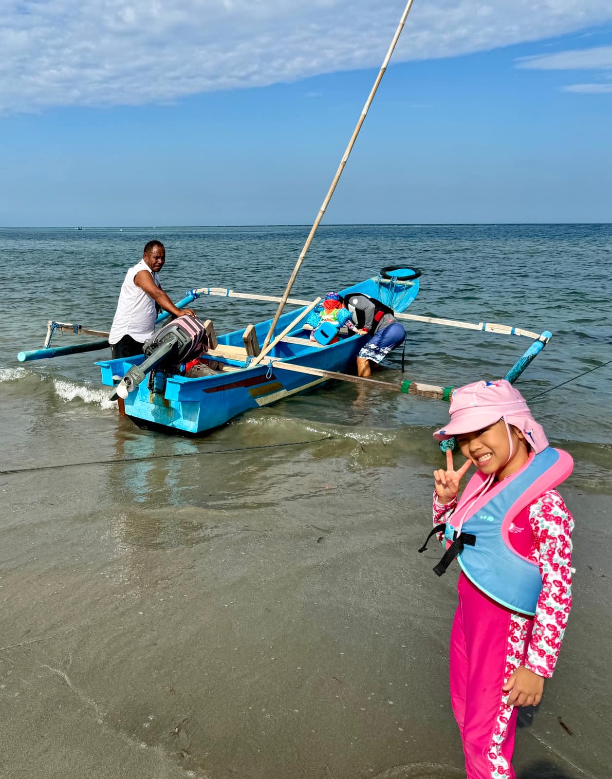 Sophie beside a small outrigger boat at the shore on Atauro Island