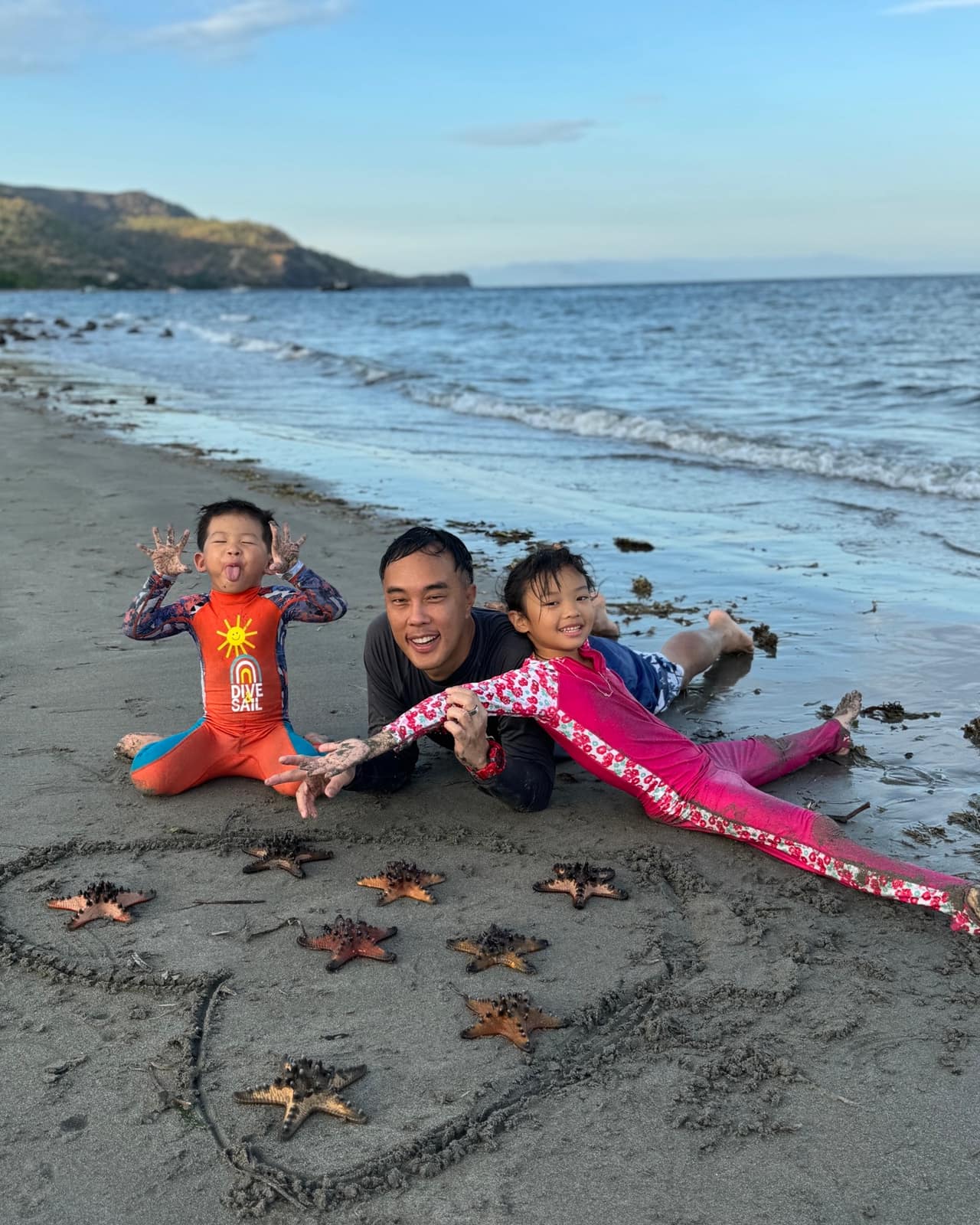Philip, Sophie and George sitting together on the beach at Atauro Island