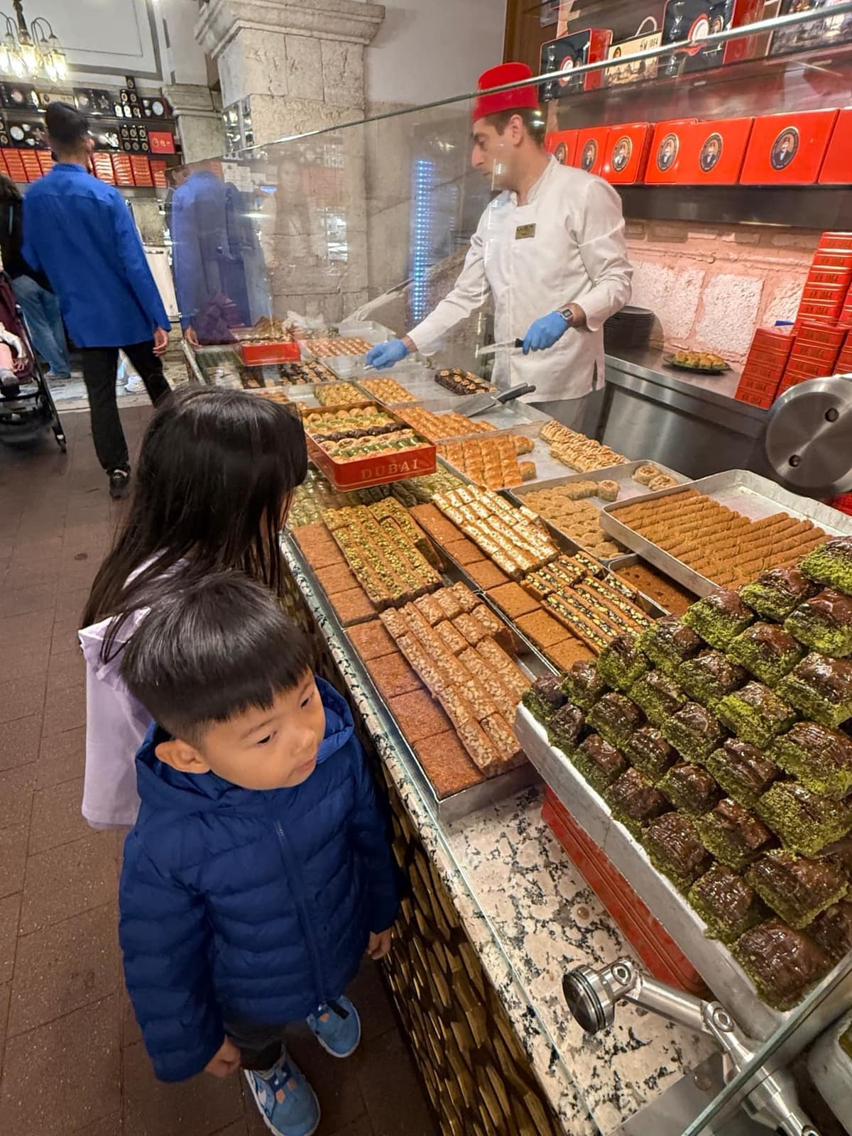 George and Sophie looking over trays of sweets at a market counter