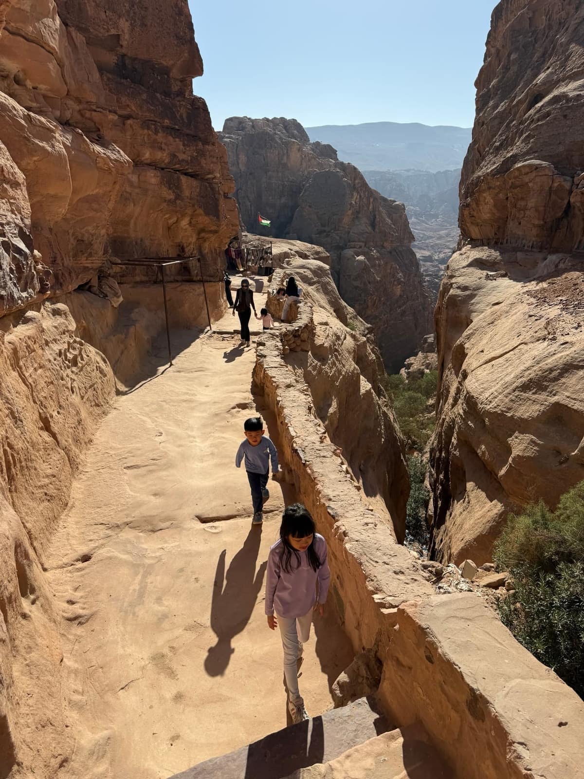 Sophie and George walking along a high sandstone path at Petra