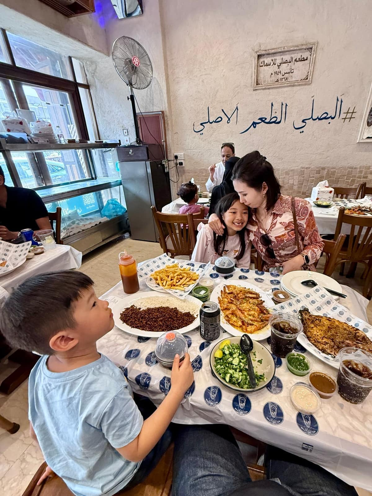 The family seated around a table filled with fish, prawns, rice and salads in Jeddah