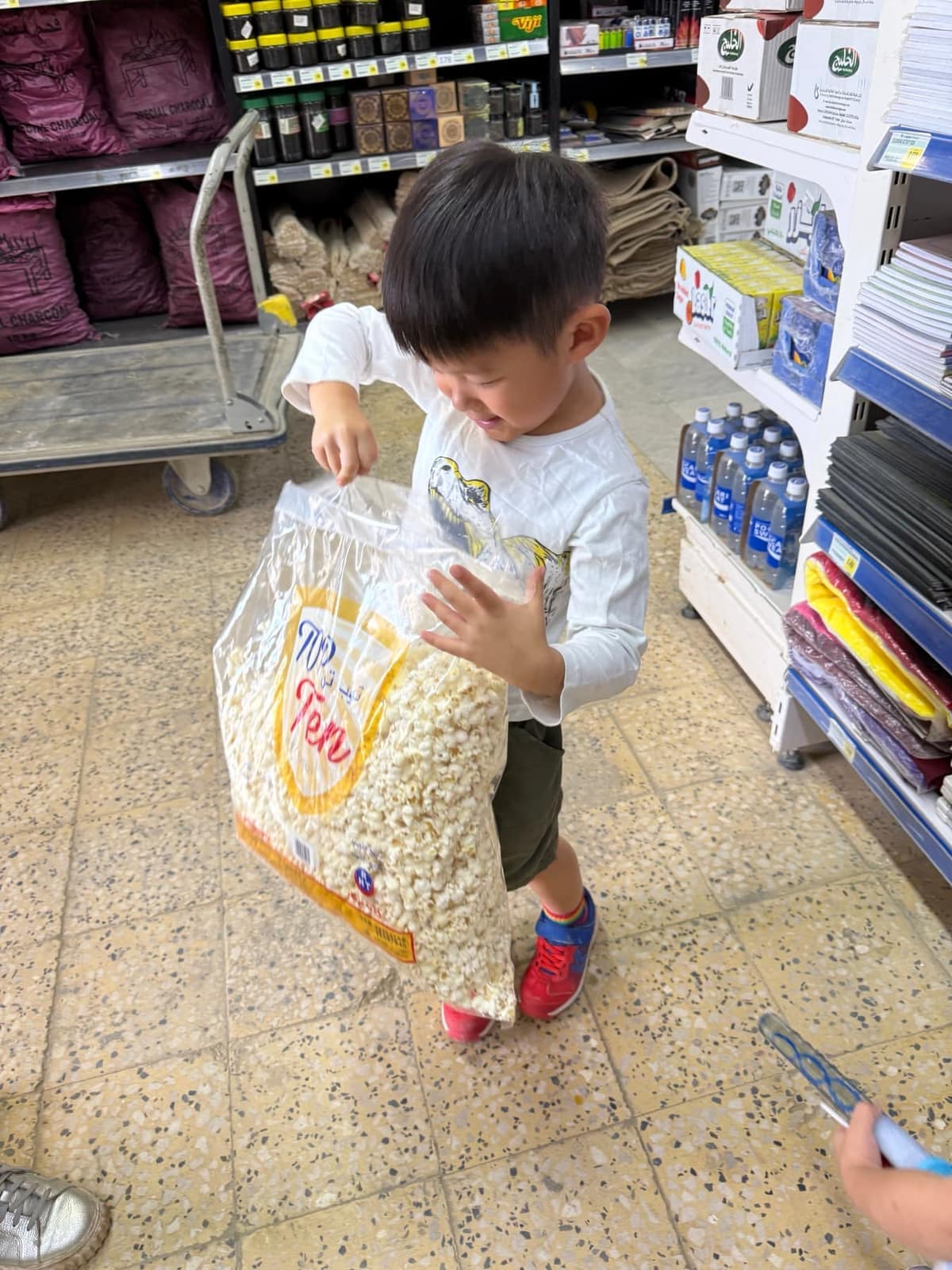 George carrying a very large bag of popcorn in a shop