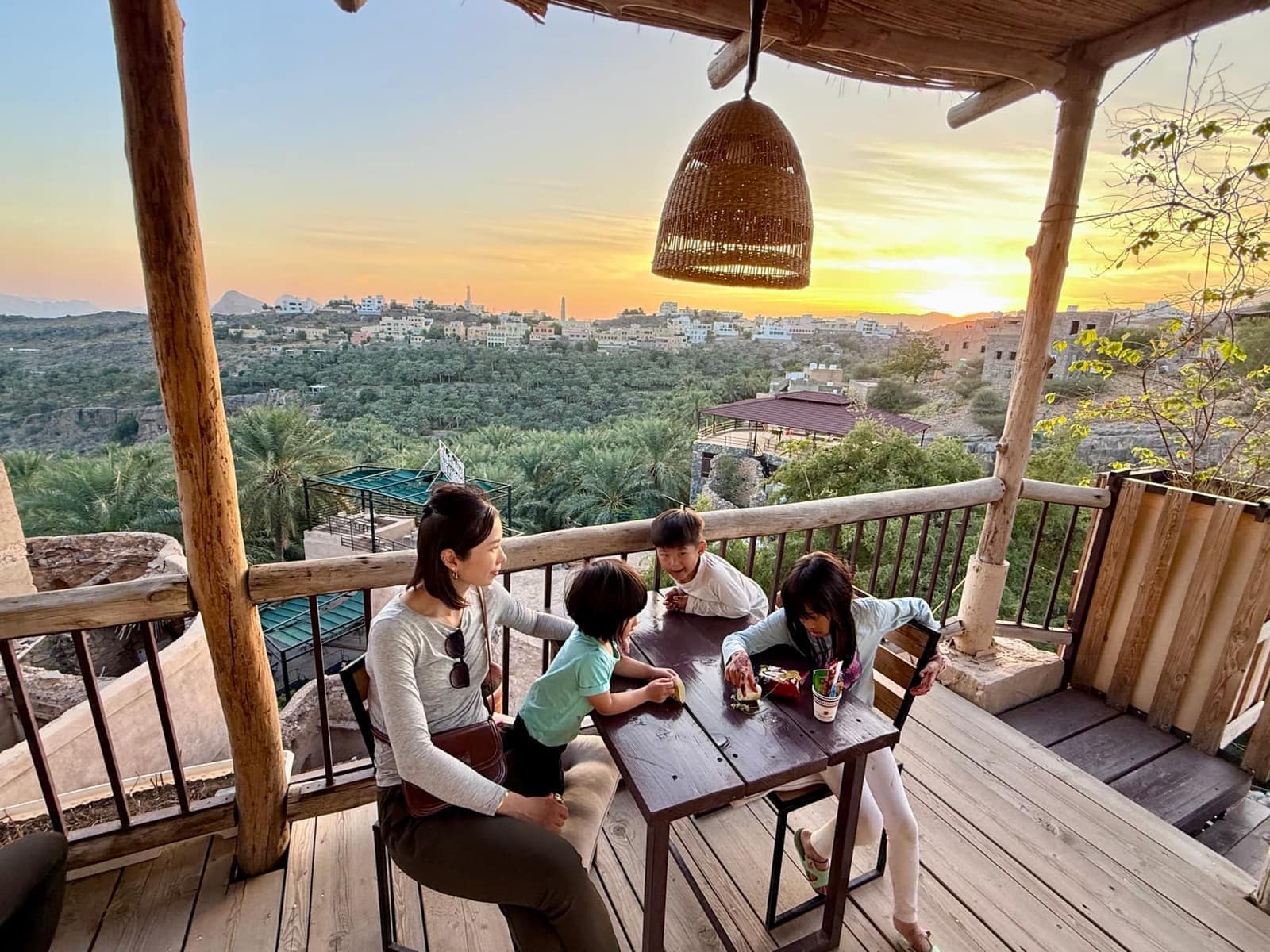 Vanessa and the children seated together above the palm groves at Misfah at sunset
