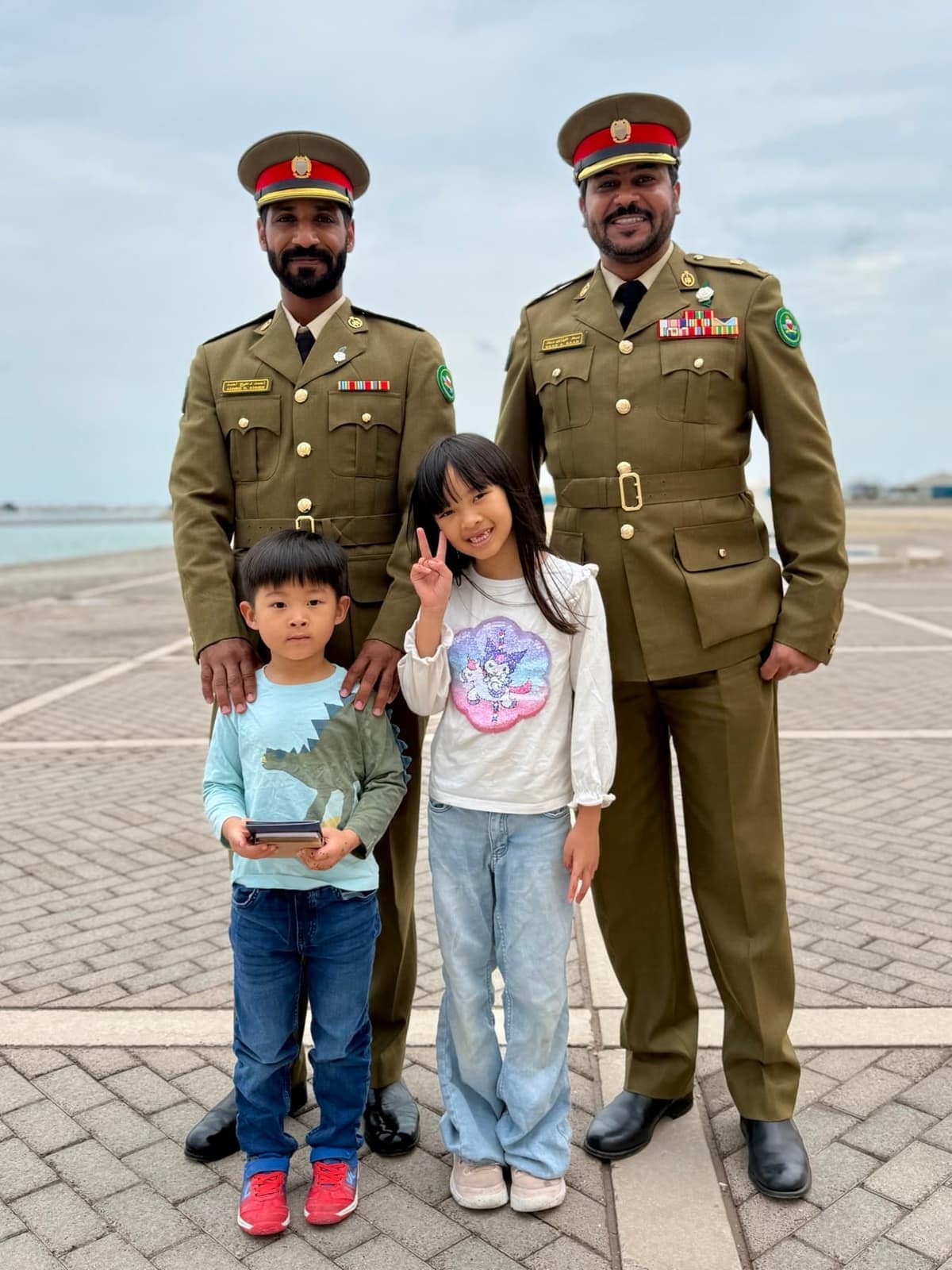 Sophie and George standing with two Bahraini soldiers on the waterfront during National Day celebrations