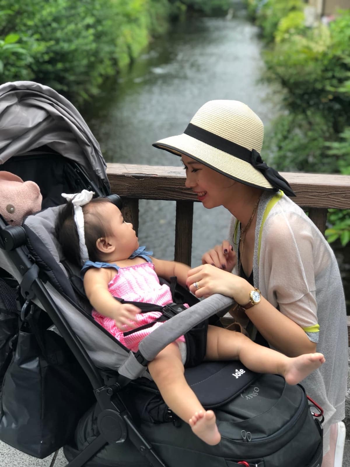 Vanessa leaning towards Sophie in her stroller beside a canal in Kyoto