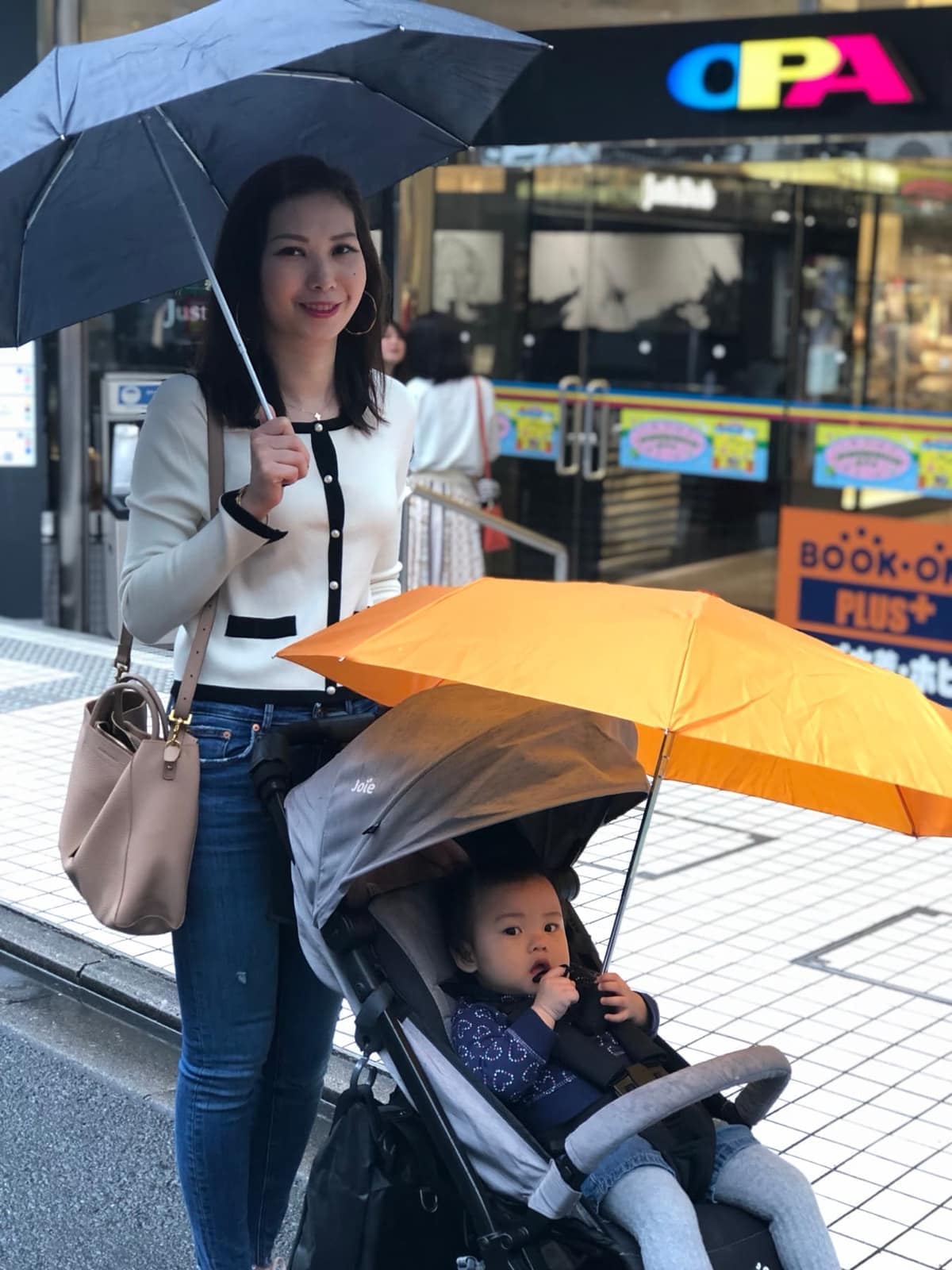 Vanessa pushing Sophie beneath umbrellas used for shade on a Kyoto street