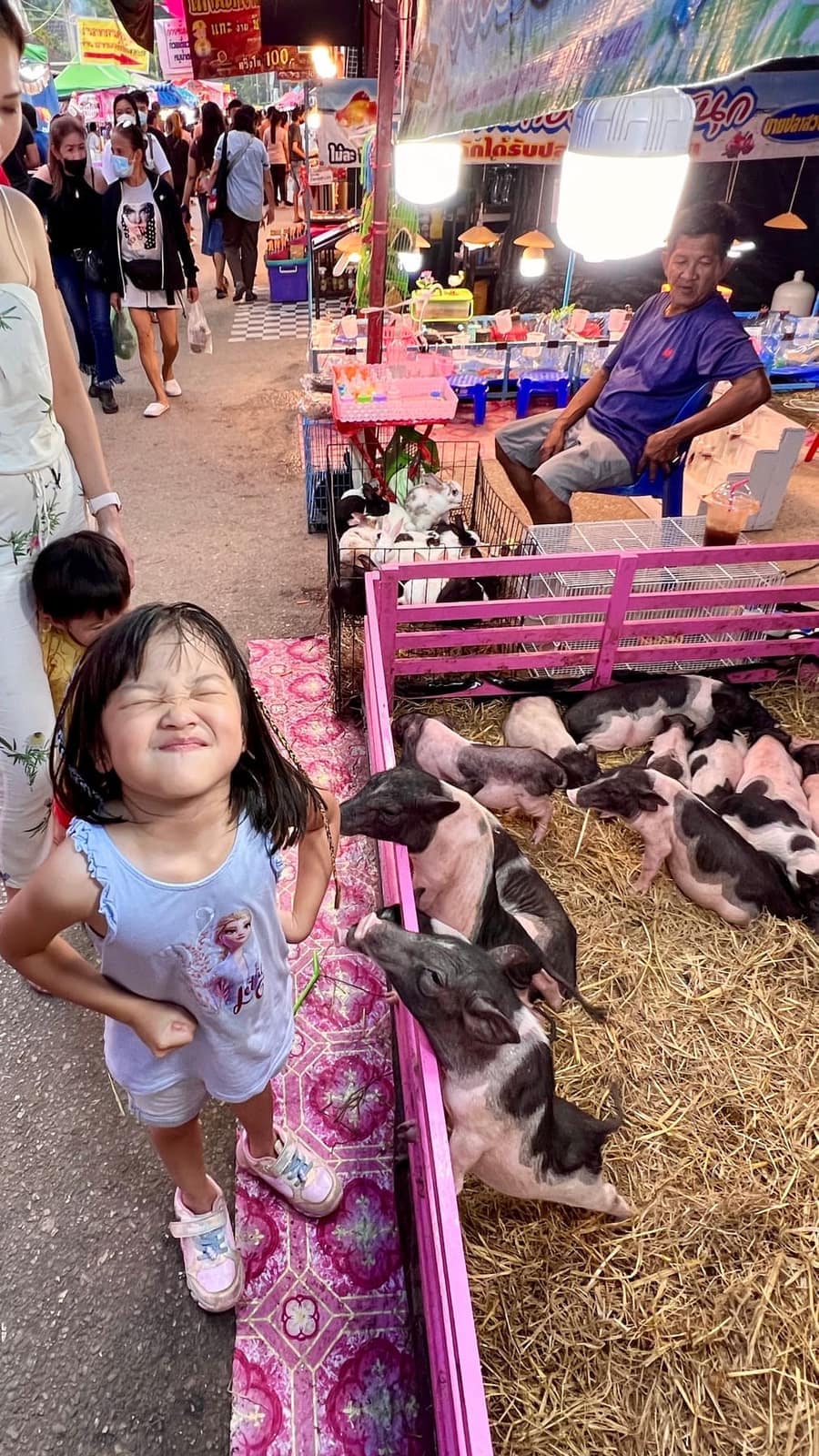 Sophie beside pigs at a night market by the Bridge over the River Kwai
