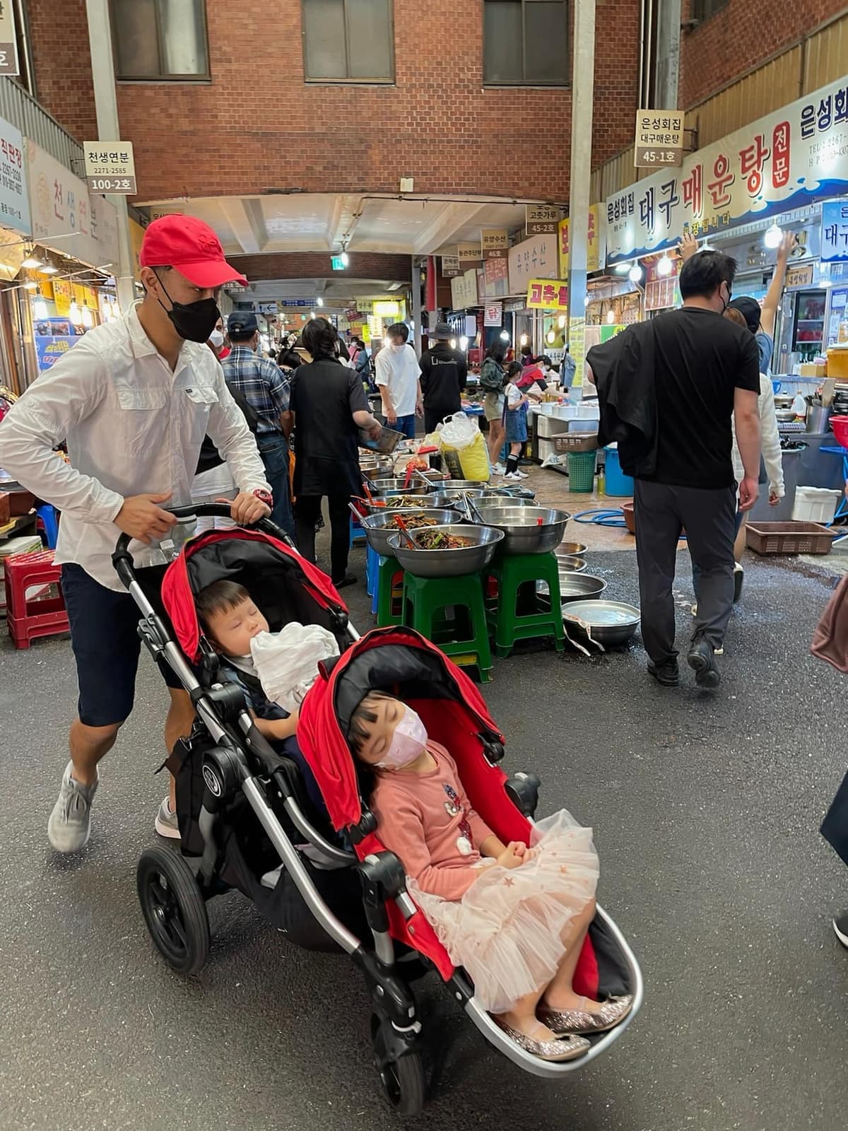 Sophie and George asleep in their stroller at a Seoul market