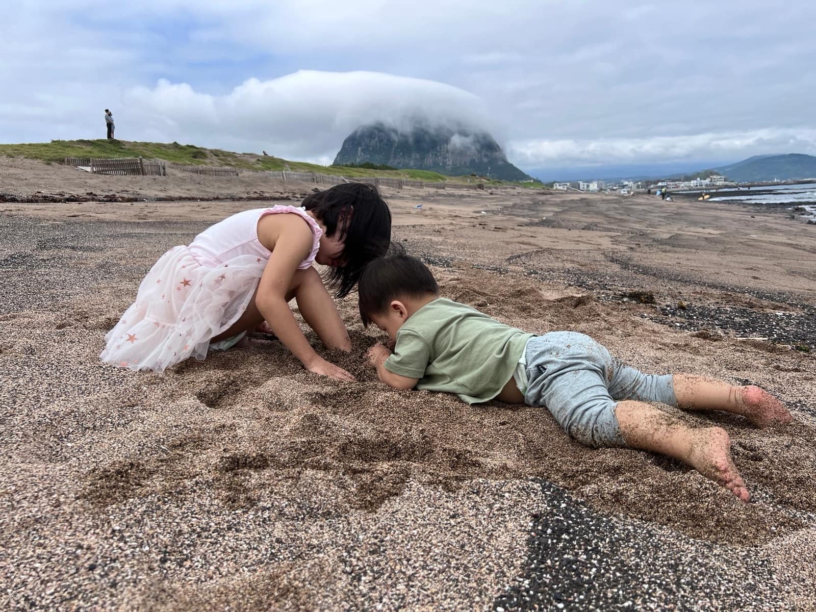 Sophie and George playing on a volcanic black-sand beach on Jeju