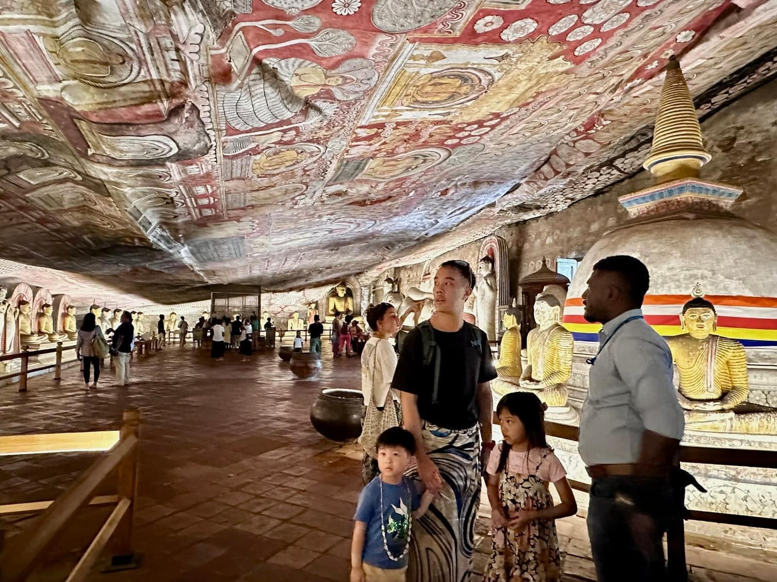 Philip and the children looking around inside Dambulla Cave Temple beneath a painted ceiling