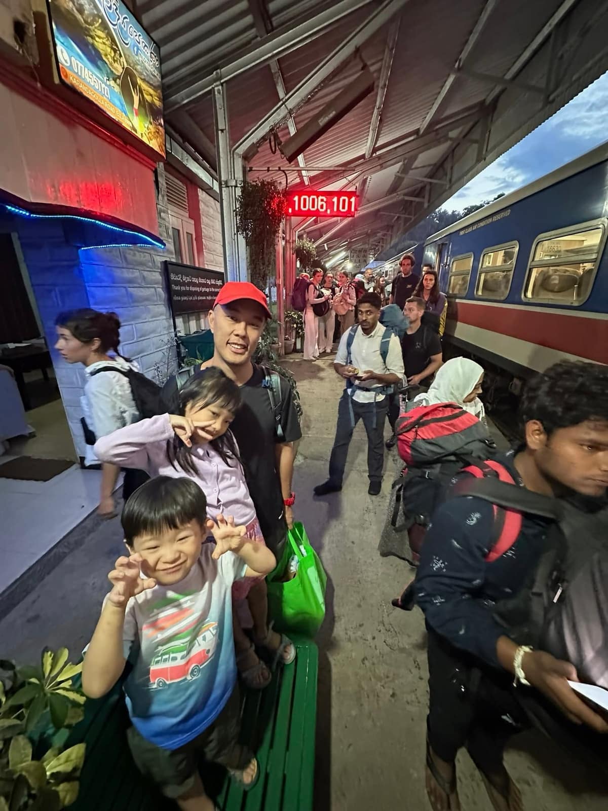 The family with luggage on a busy station platform at dusk