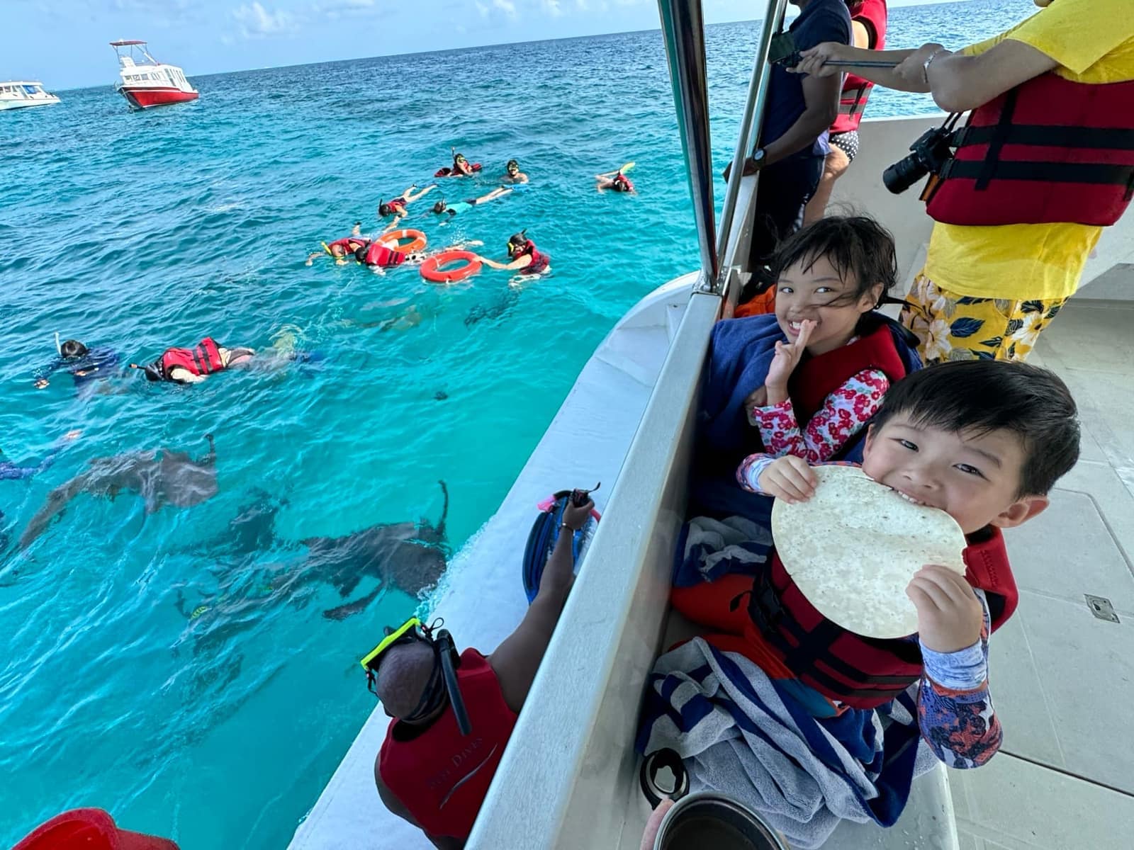 Sophie and George in life jackets looking from the boat towards sharks below