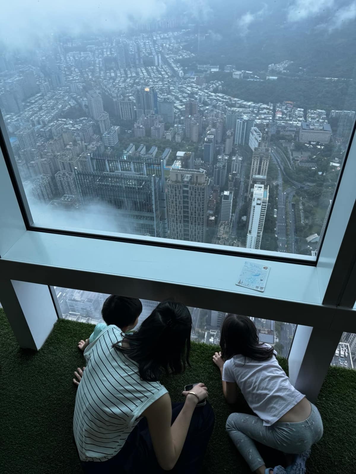 Vanessa and the children looking down through the windows of Taipei 101
