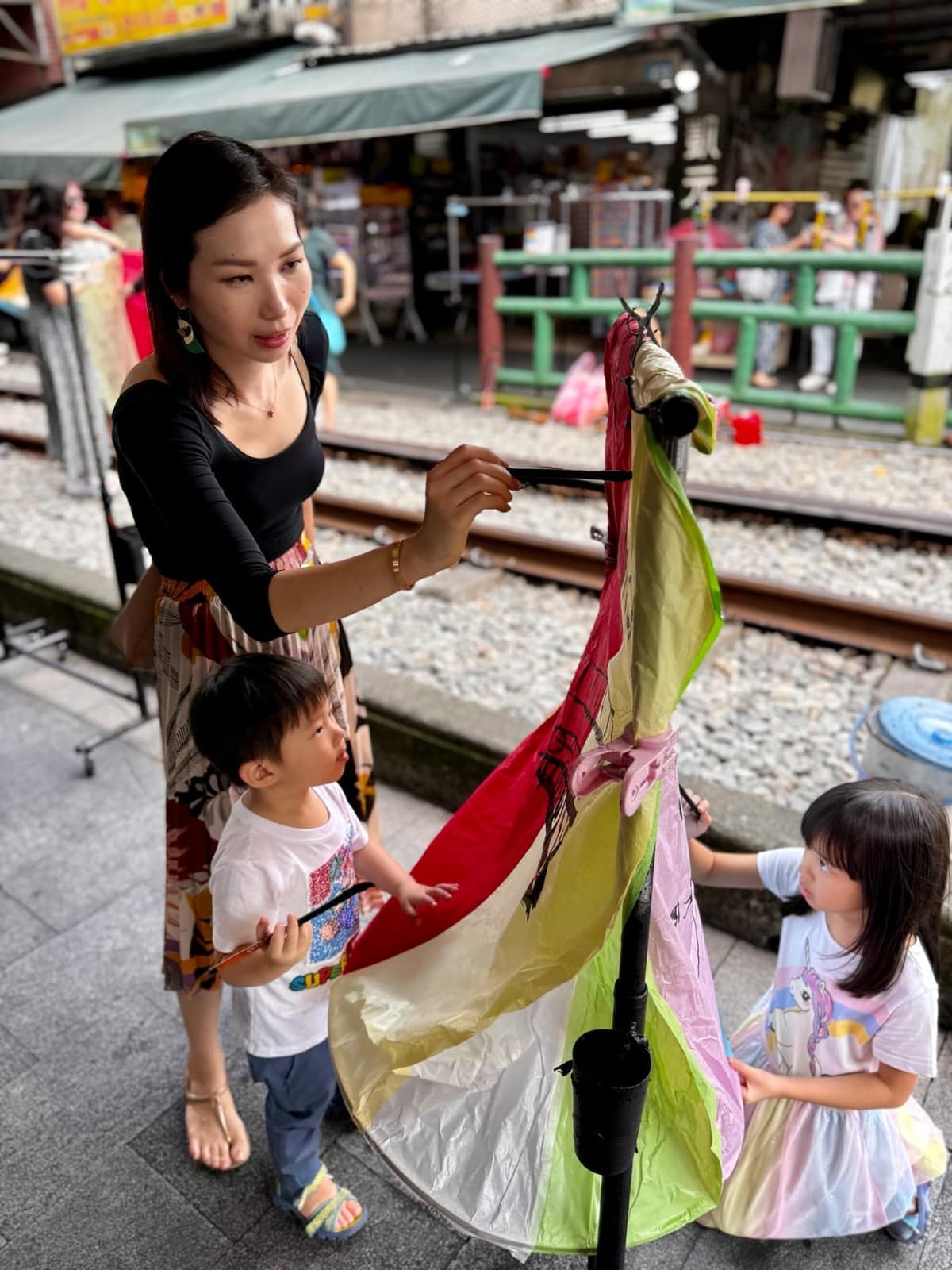 The children holding a painted sky lantern beside the railway tracks at Shifen