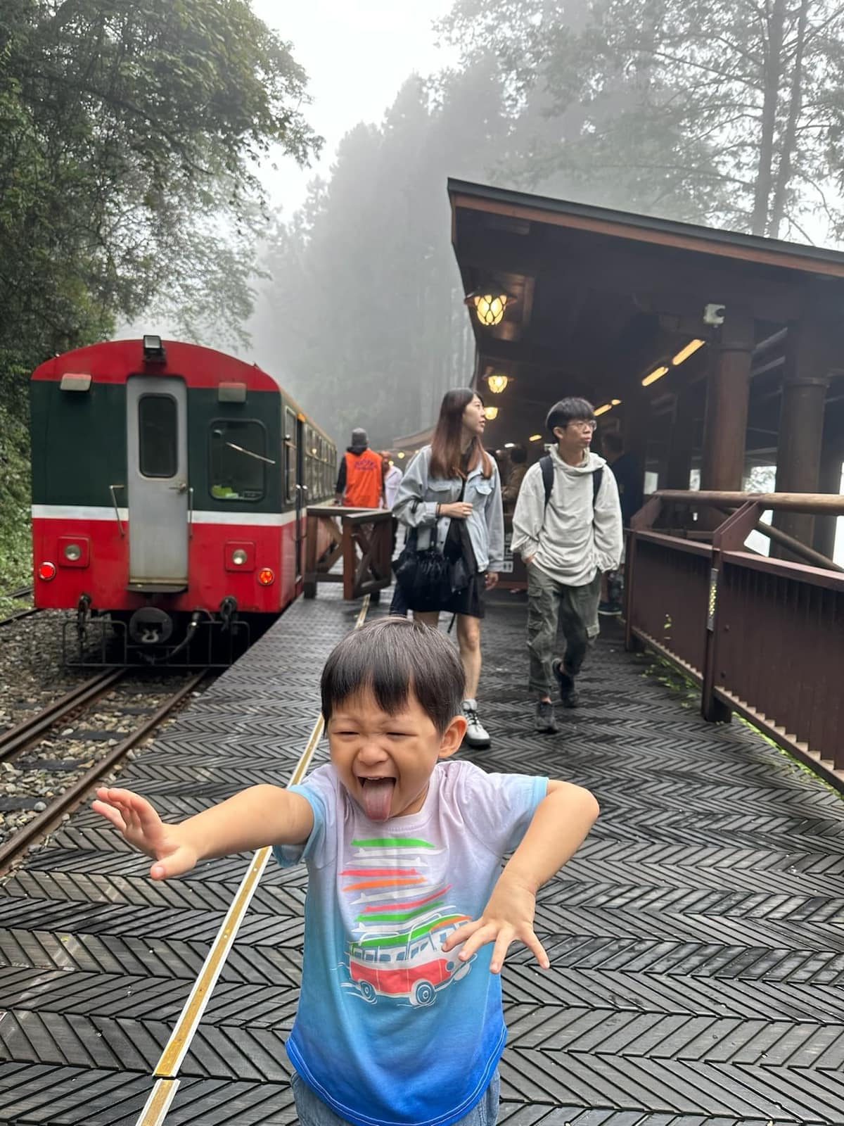 One of the children running beside a red Alishan Forest Railway train