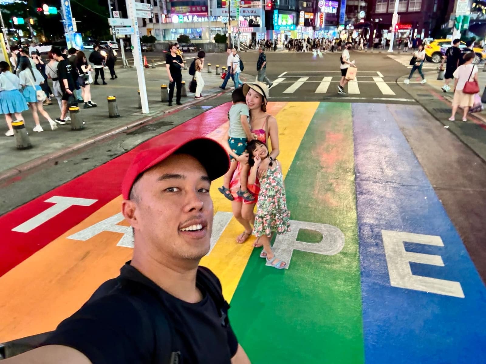 A family selfie on a brightly painted street at night in Taipei