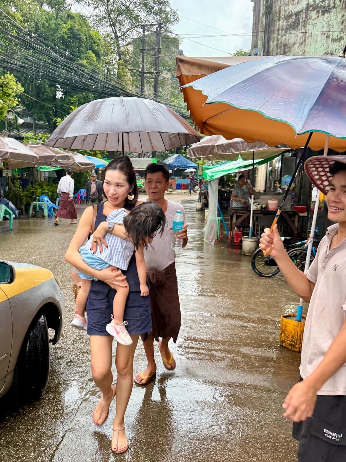 People from a food stall sheltering Vanessa and Claire with umbrellas as they walk to a taxi