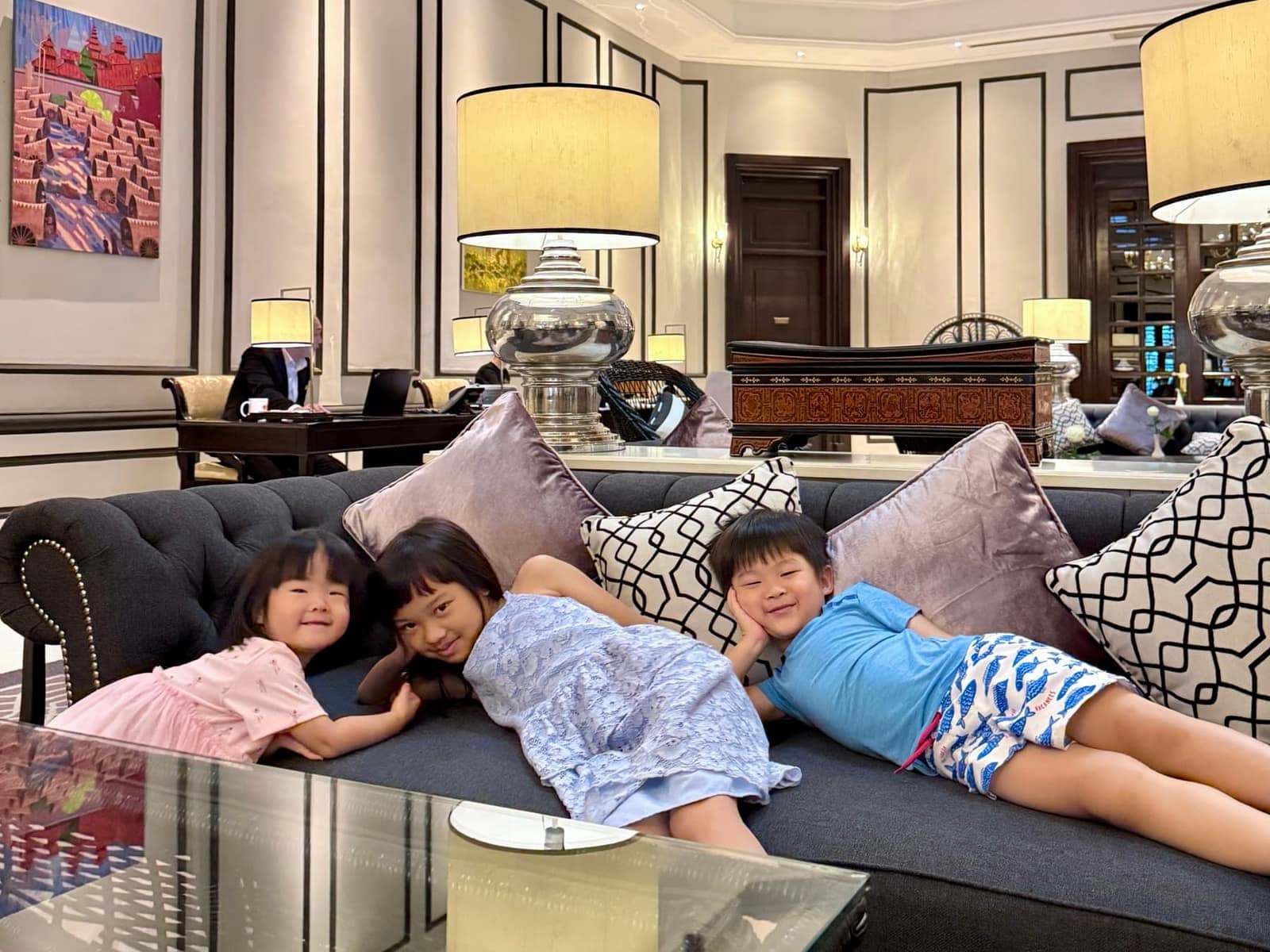Sophie, George and Claire resting together on a sofa inside The Strand Yangon
