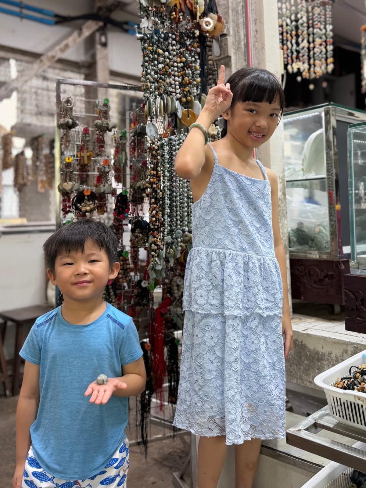 Sophie showing a jade bracelet and George holding a small souvenir at a jewellery stall